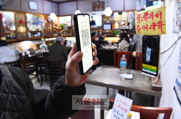 지난 달 28일 점심시간 서울 종로의 한 음식점에서 손님이 방역패스를 등록 하고 있다. 오늘부터 방역패스가 일시 중단된다. 안주영 전문기자