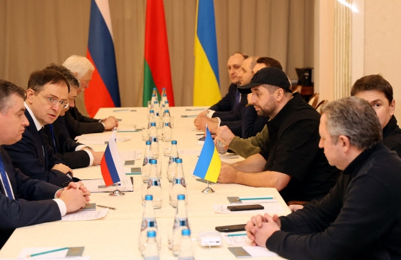 28일 벨라루스 고멜 지역에서 러시아의 우크라이나 침공 이후 처음으로 열린 양국 협상에서 대표단이 굳은 표정으로 마주 앉아 있다. 러시아 대표단인 레오니트 슬루츠키(왼쪽부터) 연방하원 의원, 블라디미르 메딘스키 대통령 고문, 안드레이 루덴코 외무부 차관, 알렉산드르 포민 국방부 차관과 대조적으로 국가 총동원령이 내려진 우크라이나 측의 다비드 아라카미아(오른쪽) 국회의원은 야구모자를 쓰고 있다. 고멜 로이터 연합뉴스