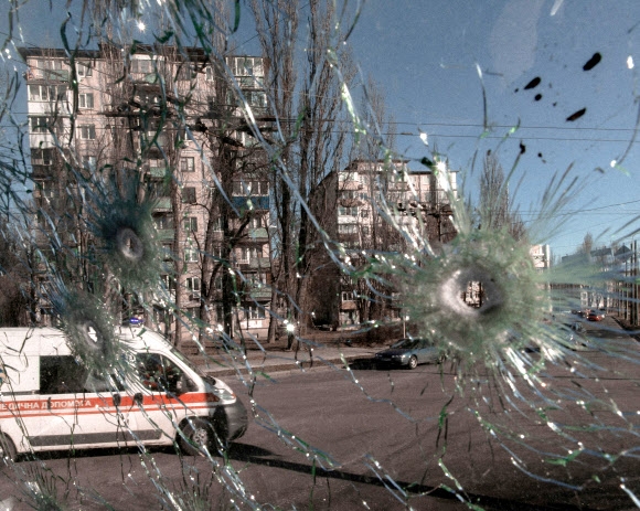러시아의 침공 닷새째인 28일(현지시간) 우크라이나 수도 키예프에서 총탄에 맞아 파손된 차량 유리창 밖으로 구급차가 지나가는 모습이 보인다.  키예프 로이터 연합뉴스