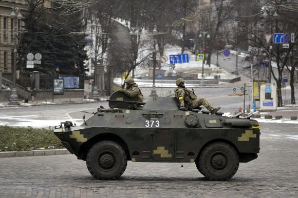 1일(현지시간) 우크라이나 수도 키예프에서 공습경보 사이렌이 울리는 가운데 텅 빈 도로를 군인들이 장갑차를 타고 달리고 있다.  AP 연합뉴스