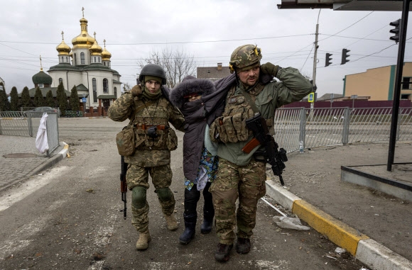 우크라이나 군인들이 6일(현지시간) 수도 키이우(키예프) 서북쪽 소도시 이르핀에서 피란길에 나선 노인을 부축해 이동하고 있다. 키이우를 향한 러시아군의 공세가 거세지면서 키이우 북쪽 지역 주민들의 목숨을 건 탈출이 계속되고 있다. 2022.3.7 이르핀 AP 연합뉴스