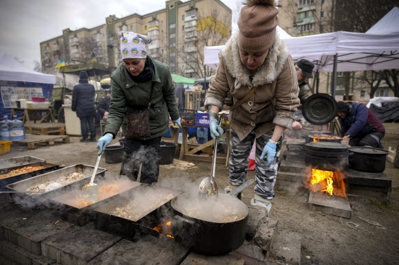 우크라이나 수도 키이우에서 음식을 나누고 있는 사람들. 러시아와 우크라이나는 3차 회담을 통해 민간인 대피를 위한 인도주의 통로를 개설하기로 합의했다고 밝혔다. AP연합뉴스