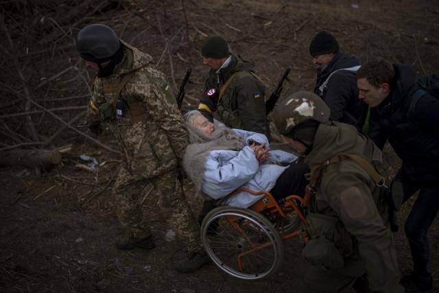 우크라이나 수도 키이우(키예프) 외곽 소도시 이프린에서 포성이 울리는 가운데 우크라이나 군인들이 휠체어를 탄 노인의 피란을 돕고 있다. 연합뉴스