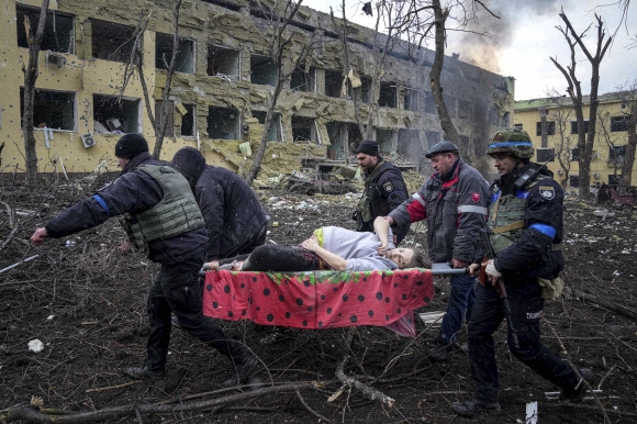 우크라이나 남부 해안도시 마리우폴의 구급대원들이 9일(현지시간) 러시아군의 무차별 폭격에 의해 파괴된 산부인과 병동에서 구조한 임부를 이송하고 있다.  마리우폴(우크라이나) AP 연합뉴스