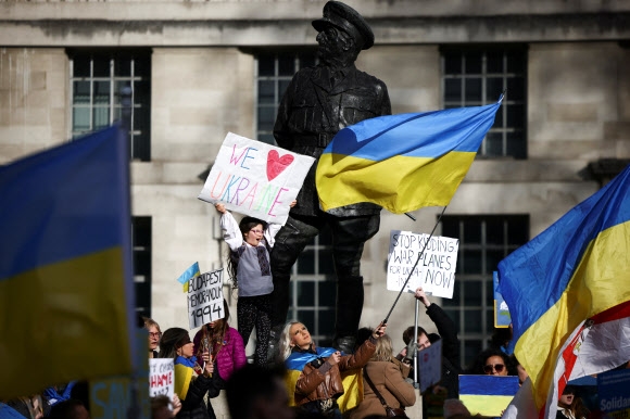 12일(현지시간) 영국 총리 관저가 위치한 런던 다우닝가 인근에서 사람들이 “우리는 우크라이나를 사랑한다” 등 손팻말을 들고 러시아 규탄·우크라이나 지지 시위를 벌이고 있다. 런던 로이터 연합뉴스