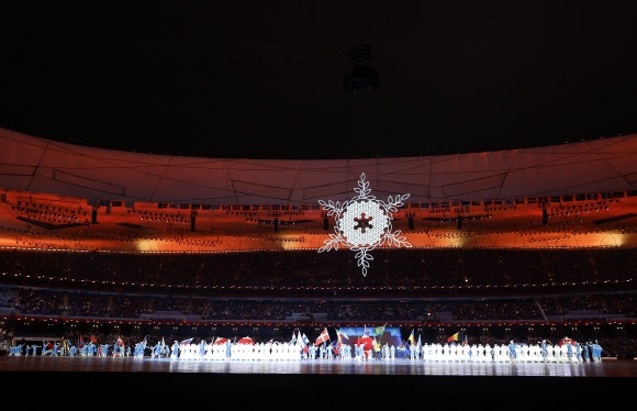 희망과 평화가 이겼다… 베이징동계패럴림픽 폐막 2022 베이징동계패럴림픽에 참가한 각국 선수단이 13일 중국 베이징 국가체육장에서 열린 패럴림픽 폐회식에서 성화 아래 국기를 들고 행진하고 있다. 베이징 로이터 연합뉴스
