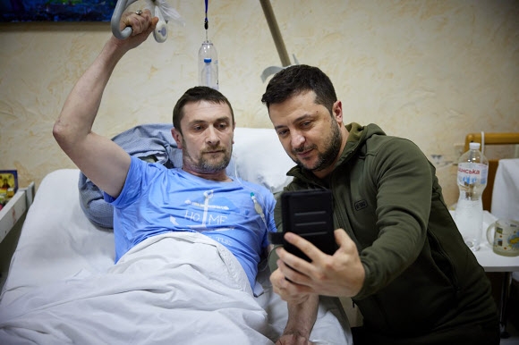 볼로디미르 젤렌스키(오른쪽) 우크라이나 대통령이 13일(현지시간) 수도 키이우(키예프)의 한 병원을 방문해 부상병과 휴대전화로 셀카를 찍고 있다.  우크라 대통령실 제공·AP 연합뉴스