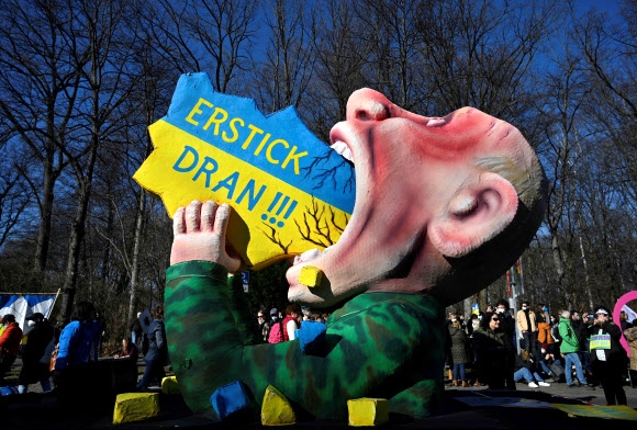 독일 베를린에 등장한 블라디미르 푸틴 러시아 대통령의 풍자 조형물. 푸틴이 삼키려는 우크라이나 지도에 ‘목에 걸렸다’라는 시위대의 규탄 구호가 적혀 있다. 베를린 연합뉴스