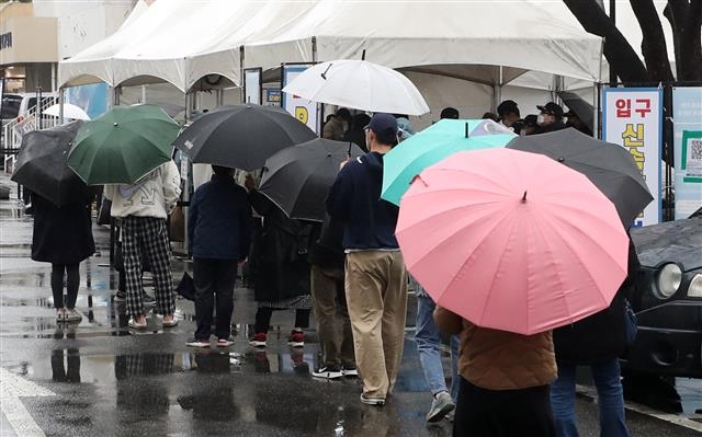 우산 쓰고 검사 기다리는 시민들