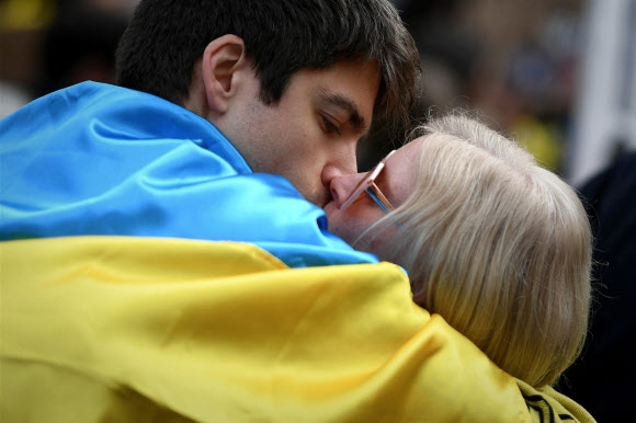 지난 13일(현지시간) 프랑스 남부 툴루즈에서 열린 러시아의 우크라이나 침공 반대 시위에서 우크라이나 국기를 두른 참가자 커플이 키스를 하고 있다. 툴루즈 AFP 연합뉴스