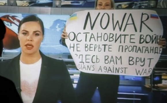 14일(현지시간) 러시아 국영 채널1 TV의 저녁 뉴스 생방송 도중 진행자 뒤로 불쑥 나타나 반전 메시지를 들어보이는 마리아 오브샤니코바. EPA 연합뉴스