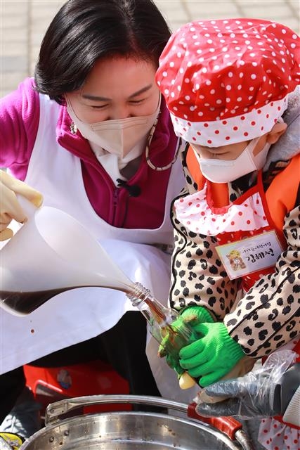 김수영(왼쪽) 서울 양천구청장이 지난 15일 신정동 양천도시농업공원에서 ‘양천장독대’ 사업에 참여하는 어린이와 함께 주민이 직접 담근 간장을 병에 옮겨 담고 있다. 양천구 제공