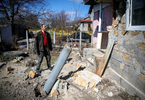 17일(현지시간) 우크라이나 수도 키이우(키예프) 북쪽 외곽에서 한 남성이 자신의 집 마당에 떨어져 꽂힌 러시아군 로켓포 잔해를 바라보고 있다. 로이터 연합뉴스