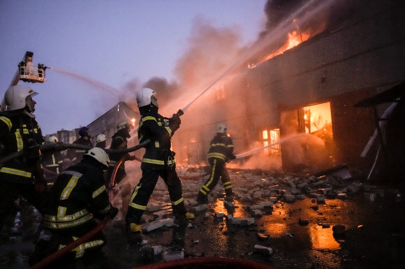 17일(현지시간) 우크라이나 수도 키이우(키예프)에서 소방관들이 러시아군의 폭격을 받은 창고 건물의 불을 끄고 있다. 러시아군은 키이우를 점령하기 위해 무차별 공격을 퍼부어 사상자와 민간 시설 피해가 급증하고 있다. 2022.3.18 AP연합뉴스