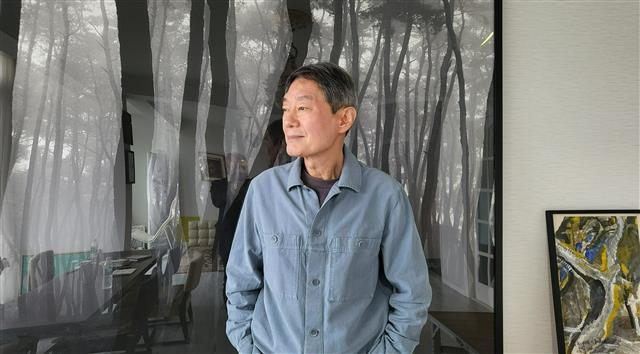 황학주 시인이 지난 18일 제주 중산간 마을 조천읍 신촌리 자택에 있는 배병우 작가의 소나무 사진 앞에서 창 너머 바다를 바라보고 있다.