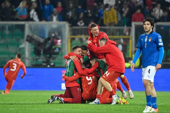 북마케도니아 축구대표탬이 24일 이탈리아를 1-0으로 꺾고 카타르월드컵 유럽예선 플레이오프 최종전 진출을 확정한 뒤 망연자실해 하는 상대팀 미드필더 산드로 토날리를 앞에 두고 서로 뒤엉켜 기뻐하고 있다. [EPA 연합뉴스]