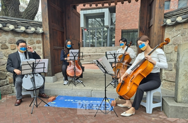 배일환 이화여대 관현악과 교수가 25일 낮 12시 반 서울 중구 정동길에서 관현악과 제자들과 함께 우크라이나 전쟁의 중단을 촉구하는 ‘평화를 위한 작은 음악회’를 열고 있다. 이들이 쓴 우크라이나 국기 색 마스크는 지나가던 시민이 평화의 뜻에 동참하기 위해 기부한 마스크다. 곽소영 기자