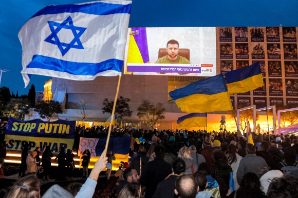 지난 20일(현지시간) 러시아의 우크라이나 침공에 반대하는 이스라엘 사람들이 텔아비브 하비마 광장에 모여 볼로디미르 젤렌스키 우크라이나 대통령의 이스라엘 의회 화상 연설이 방송되는 것을 보고 있다. 텔아비브 AFP 연합뉴스