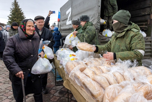 우크라이나 돈바스 지역 친러 분리주의 반군 정부인 루간스크인민공화국(LPR)이 러시아군의 지원하에 최근 점령한 트로히즈벤카 마을에서 27일(현지시간) 침략군이 나눠 주는 구호식량을 주민들이 받고 있다. 트로히즈벤카 타스 연합뉴스