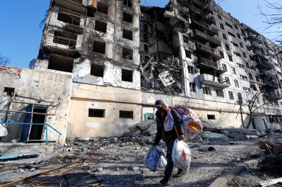러시아군 폭격으로 무참히 파괴된 우크라이나 남부 항구도시 마리우폴의 아파트에서 28일(현지시간) 한 남성이 가재도구를 챙겨 나오고 있다. 2022.3.29 마리우폴 로이터 연합뉴스