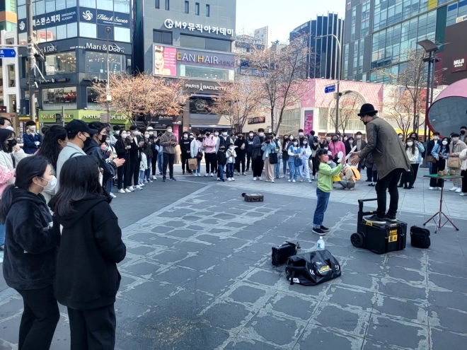 80여명의 시민이 3일 오후 1시 서울 서대문구 연세로에서 거리공연을 하는 마술사를 중심으로 반원 형태로 둘러싸고 봄날의 공연을 즐겼다.