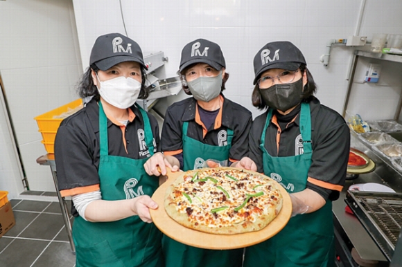 서울 마포구 합정동 마포시니어클럽 1층에 있는 ‘피자마루 마포합정점’에서 일하는 어르신들이 직접 만든 피자를 들어 보이고 있다. 마포구 제공