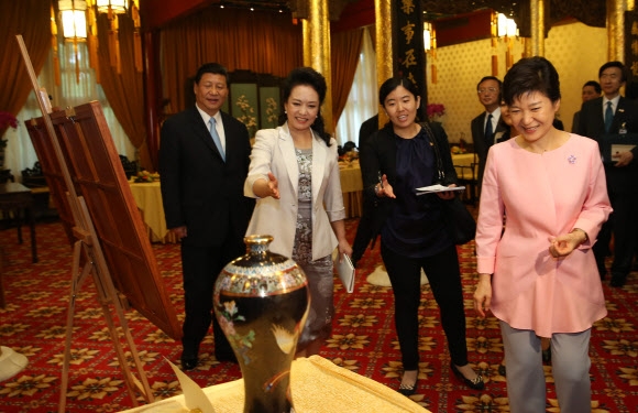 중국을 국빈방문했던 박근혜 당시 대통령이 지난 2013년 베이징에서 시진핑 국가주석(왼쪽) 내외와 오찬을 함께한 뒤 펑리위안 여사에게서 법랑 항아리 선물에 대한 설명을 듣던 모습이다. 2013.6.28.연합뉴스