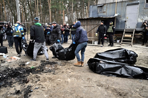 5일(현지시간) 우크라이나 수도 키이우 북서쪽 외곽 소도시 부차에서 우크라이나 당국 관계자들이 불에 탄 민간인 시신 6구를 수습하고 있다. 러시아군이 키이우 지역에서 철수한 뒤 부차에서는 민간인 최소 410명의 시신이 발견됐으며 이들 중 상당수에게서 총상과 고문, 성폭력 등의 흔적이 확인됐다. 볼로디미르 젤렌스키 우크라이나 대통령은 이날 유엔 안전보장이사회 회의에서 화상 연설을 통해 “러시아군은 오직 재미를 위해 민간인들을 학살했다”고 규탄했다. AFP 연합뉴스