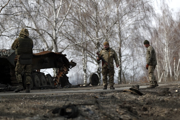 우크라이나 군인들이 지난달 31일 우크라이나마카리우로 향하는 도로에서 교전으로 파손된 러시아 탱크 잔해를 점검하고 있다. EPA연합뉴스