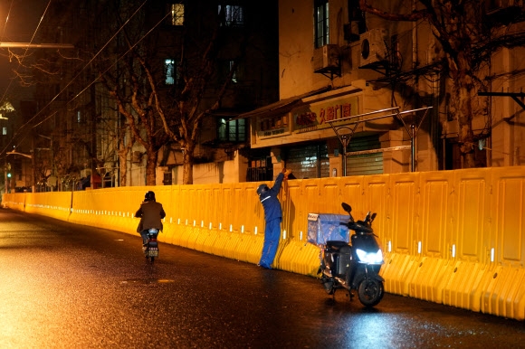 코로나19 확산 방지를 위해 도시가 봉쇄된 중국 상하이에서 한 배달원이 봉쇄 장벽 너머의 주민에게 배달 물품을 전하고 있다. 2022.3.31 로이터 연합뉴스