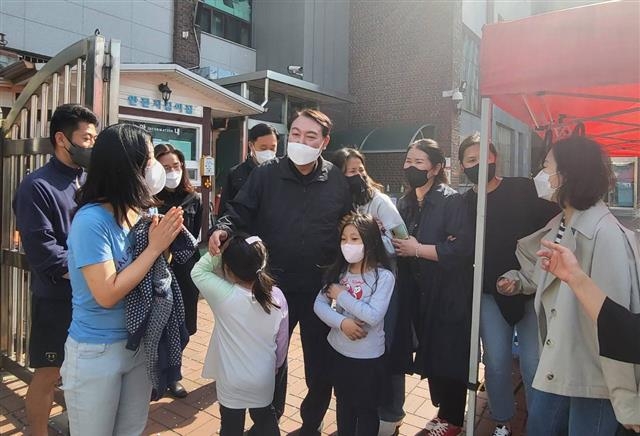 윤석열 대통령 당선인이 지난 9일 모교인 서울 성북구 대광초등학교를 편안한 차림으로 깜짝 방문해 학생들과 인사를 나누고 있다. 윤 당선인은 이날 열린 학교 굿즈 판매 행사에서 학생들이 판매하고 있던 가방 두 개를 구입했다.  뉴스1