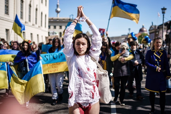 부활절을 맞아 16일(현지시간) 독일 베를린에서 러시아를 규탄하는 반전 평화시위가 열렸다. 손을 묶고 하얀 옷에 인공 피를 묻힌 한 여성과 함께 “러시아 전쟁을 멈춰라”라고 적힌 플래카드와 우크라이나 국기를 든 참가자들이 행진을 하고 있다. 베를린 EPA 연합뉴스