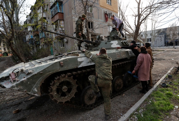 우크라이나 남부 마리우폴을 러시아군과 친러시아 성향 무장조직이 거의 장악한 가운데 친러 무장조직 대원들이 17일(현지시간) 민간인들이 탱크 위에 올라오도록 손을 잡아주고 있다. 마리우폴 로이터 연합뉴스 