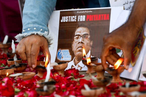 집단 린치로 살해당한 스리랑카인을 애도하기 위해 파키스탄 카라치 시민들이 그의 사진 앞에 장미 꽃잎을 놓고 석유 램프에 불을 켜고 있다. 2021.12.5 로이터 연합뉴스