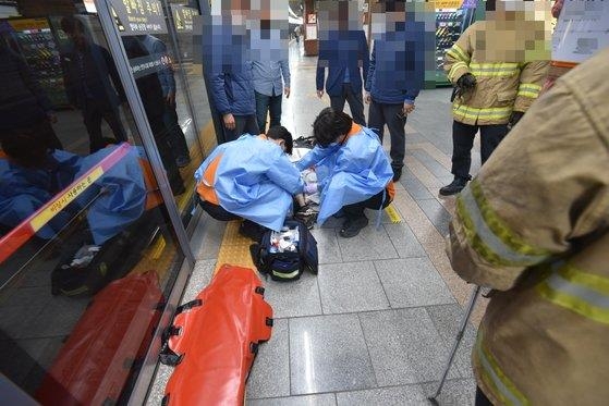 지난 16일 서울 지하철 3호선 동대입구역에서 지체장애인이 승강장과 열차 사이에 다리를 끼는 사고가 발생해 소방대원들이 응급처치를 하고 있다. 서울중부소방서 제공