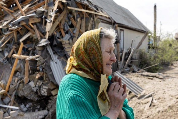 23일(현지시간) 우크라이나 동부 도네츠크주 리만에서 한 여성이 러시아군의 포격으로 산산이 부서진 이웃집 앞에서 슬퍼하고 있다. 2022.4.23 로이터 연합뉴스