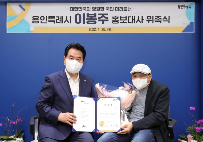 백군기(왼쪽)시장이 25일 국민 마라토너 이봉주 선수에게 홍보대사 위촉장을 전달하고 기념촬영을 하고 있다. 용인시 제공 