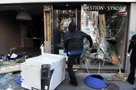1일(현지시간) 프랑스 파리에서 열린 노동절 시위에서 한 시위 참가자가 거리의 점포 유리창을 부수고 있다. 2022.5.1 AFP 연합뉴스