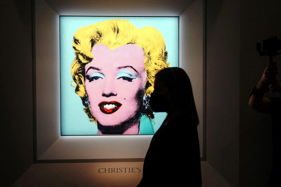 한 여성 관객이 지난 3월 21일(현지시간) 미국 뉴욕 크리스티 경매장에서 미국 팝아트 작가 앤디 워홀의 ‘매릴린 먼로’ 초상화 앞을 지나고 있다. 뉴욕 로이터 연합뉴스