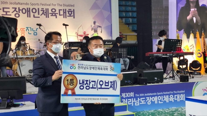 이기장(오른쪽) 뉴스깜 대표가 제 30회 전남장애인체육대회 개막식에서 경품 1등에 당첨돼 받은 오브제 냉장고(500만원 상당)를 제세공과금까지 더해 순천시장애인협회에 기부해 큰 감동을 주고 있다. 왼쪽은 문금주(전남도 행정부지사) 전남도지사 권한대행. 