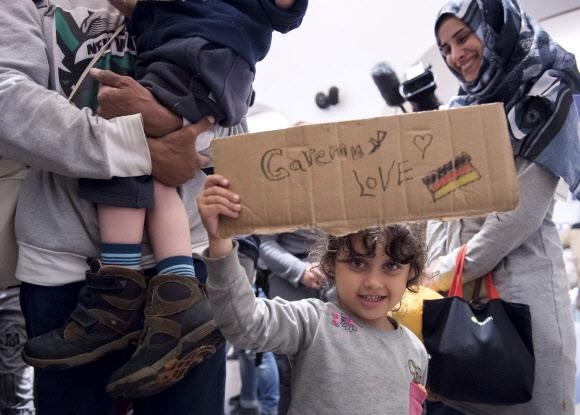 2015년 9월 시리아 내전을 피해 독일 중부도시 잘펠트 기차역에 도착한 한 난민 소녀가 ‘사랑해요 독일’이란 문구와 그림이 적힌 골판지를 들어 보이고 있다. 서울신문 DB