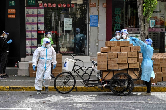 두 달 가까이 봉쇄 중인 중국 경제수도 상하이 징안구 지역에서 요원들이 주민들에게 나눠줄 식료품을 자전거에 싣고 있다. 베이징 AFP 연합뉴스