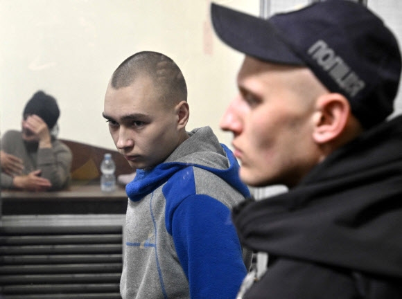 우크라 법정 선 러 병사 18일에는 개전 이후 첫 전범 재판이 열렸다. 우크라이나 민간인을 사살한 혐의로 구속기소된 러시아군 하사 바딤 시시마린(왼쪽)이 우크라이나 키이우 법원에서 열린 전쟁범죄 법정에서 피고인석에 서 있다. 키이우 AFP 연합뉴스