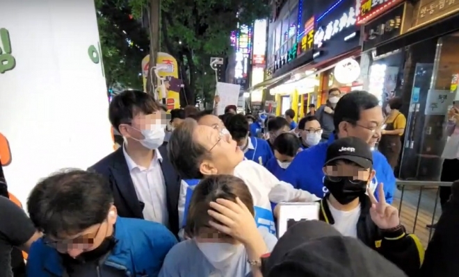 이재명 더불어민주당 총괄선거대책위원장이 20일 저녁 인천 계양구에서 거리 유세를 하던 중 철제 그릇에 맞자 그릇이 날아온 방향을 보고 있다. 유튜브 이재명 TV 캡처