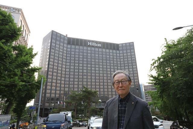 자신이 디자인한 힐튼호텔을 배경으로 서 있는 건축가 김종성. 송인호 작가 제공