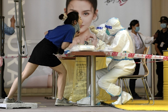 지난 22일 중국 베이징의 한 쇼핑몰에서 젊은 여성이 코로나19 핵산 검사를 받고 있다. 베이징 AP 연합뉴스