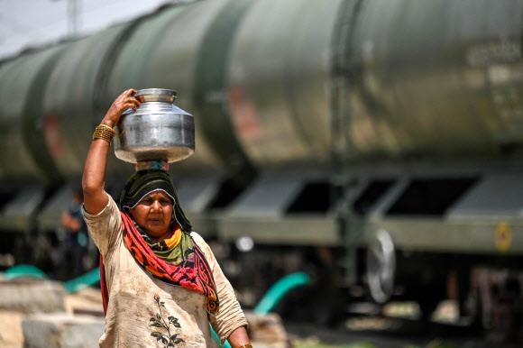 한 여성이 지난 11일 인도 라자스탄주 팔리에 도착한 식수 수송열차에서 받은 물을 담아 옮기고 있다.  팔리 AFP 연합뉴스