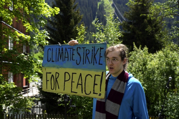 세계경제포럼(WEF)이 열리고 있는 스위스 다보스에서 한 기후 위기 활동가가 우크라이나 국기 색깔의 손팻말을 들고 서 있다. 2022.5.26 AP 연합뉴스