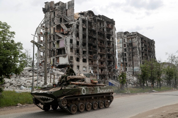 장갑차에 탄 친러시아군 장병들이 우크라이나 루한시크주 포파스나 마을에서 파괴된 주택건물을 지나고 있다. 2022.5.26 로이터 연합뉴스