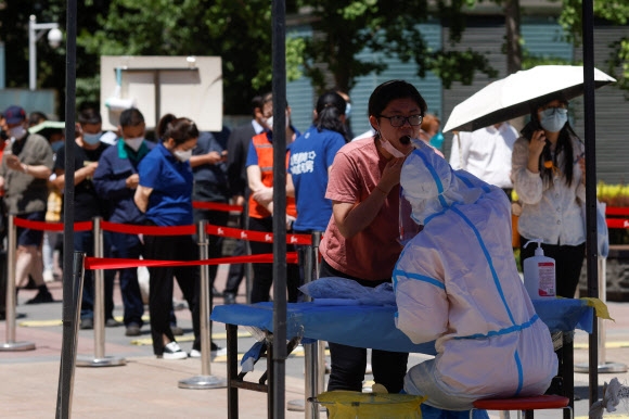중국 베이징 중앙업무지구(CBD)의 한 코로나19 검사장에서 방역복을 입은 검사요원이 주민의 검체를 체취하고 있다. 2022.5.30 로이터 연합뉴스